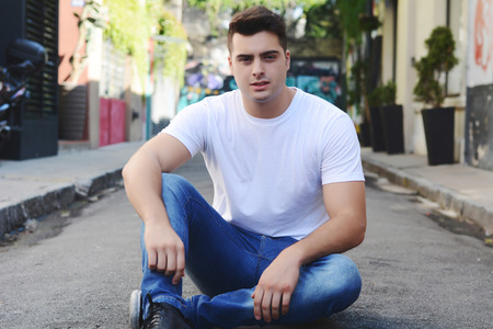 Portrait of a young handsome man sitting at the streetの写真素材