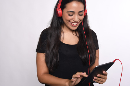 Young beautiful woman listening to music with her tablet indoor. Isolated white background.