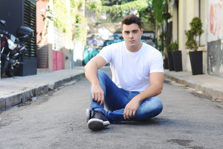 Portrait of a young handsome man sitting at the streetの写真素材