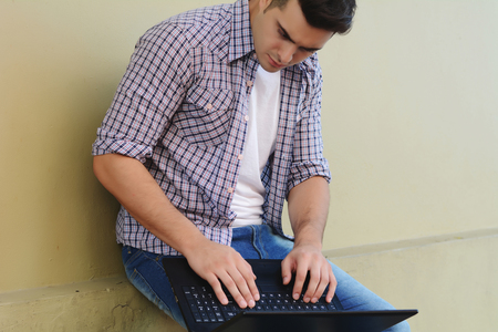 Young handsome man using his laptop outdoors.の写真素材