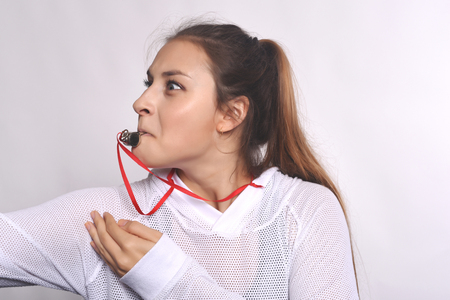 Portrait of athlete and furious young woman with whistle. Isolated white background.