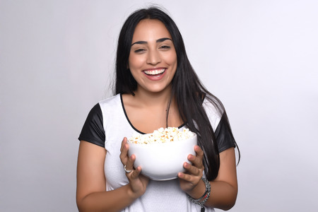 Young beautiful woman eating popcorn. Isolated white backgroundの写真素材