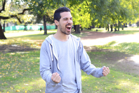 Portrait of young latin man doing success gesture in a park. Outdoors.