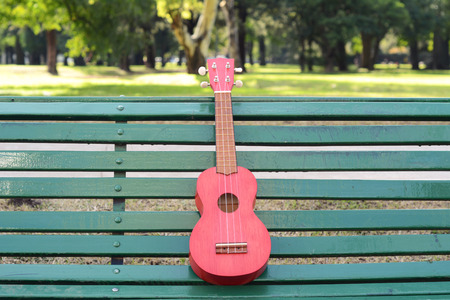 A ukulele on a park bench. Outdoors.の写真素材