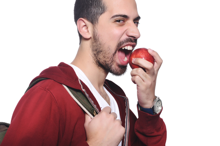 Portrait of young latin student with an apple and backpack. Isolated white background.の写真素材