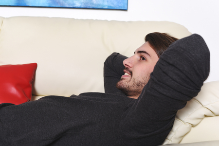 Close up to happy young man lying on couch and relaxing. Indoor.の写真素材