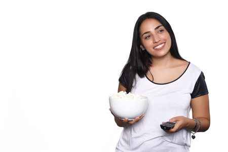 Young beautiful woman eating popcorn and watching tv. Isolated white backgroundの写真素材