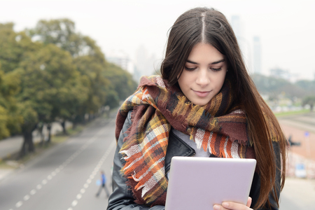Portrait of a young beautiful woman using her tablet. Outdoors. Urban scene.の写真素材