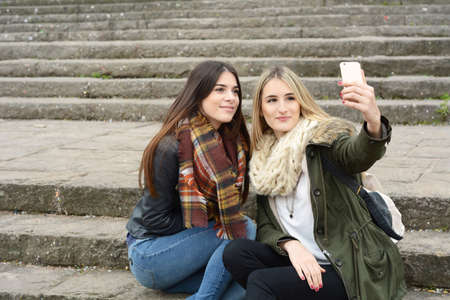 Portrait of two young girlfriends taking selfie with smartphone on a trip together. Tourism concept....