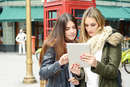 Portrait of two young girlfriends on a trip together and using the tablet. Tourism concept. Outdoors.の写真素材
