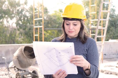 Portrait of a beautiful female architect at a construction site with blueprints. Outdoors.の写真素材