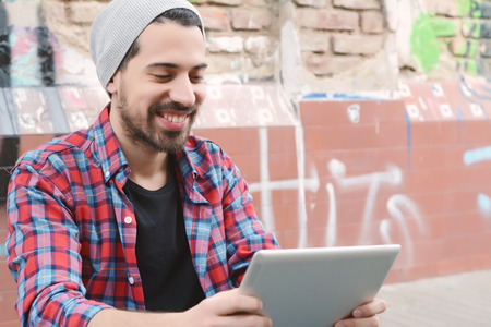Young latin man touching at tablet at the street.