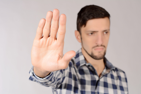 Young man doing stop gesture with hand. Isolated white background.の写真素材
