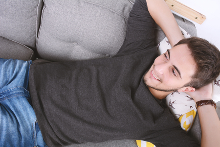 Attractive young man llying and relaxed on couch. Indoors.の写真素材