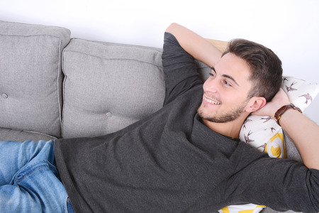 Attractive young man llying and relaxed on couch. Indoors.