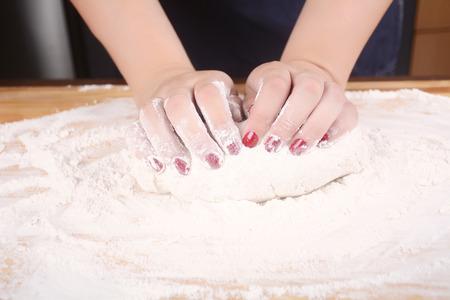 Close-up of woman hands kneading dough on wooden table. cooking and baking concept.の写真素材
