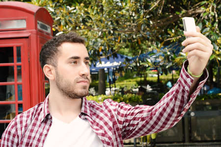 Portrait of a young latin man taking a selfie with smartphone. Outdoors.