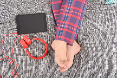 Man with headphones and digital tablet on bed. Indoors.の写真素材