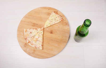 Close-up of bottle of beer and pizza on table. Indoors.の写真素材