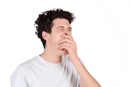 Portrait of a young man yawning. Isolated white background.の写真素材