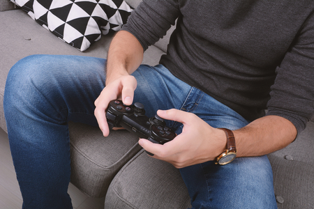 Portrait of young man playing videogames and sitting on couch. Indoors.の写真素材