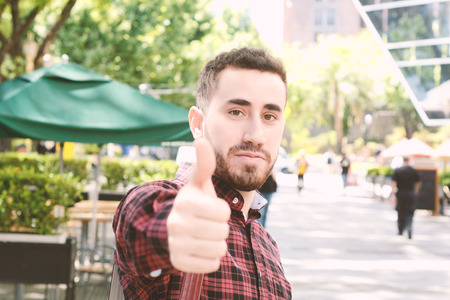 Portrait of young latin man doing ok gesture. Outdoors.の写真素材