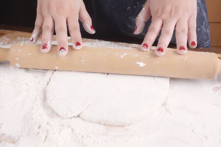Close-up of woman rolling dough with rolling pin. Cooking concept.