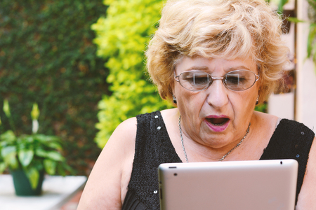 Portrait of an elderly woman using digital tablet. Outdoors.