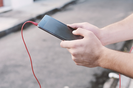 Young latin man using a tablet with headphones on the street.の写真素材