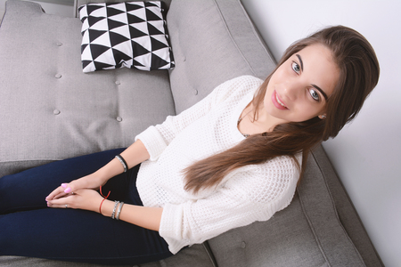 Beautiful youg woman sitting and relaxed on couch.の写真素材