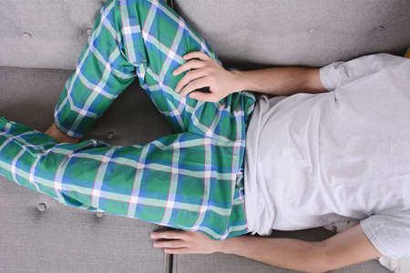 Attractive young man llying and relaxed on couch. Indoors.の写真素材