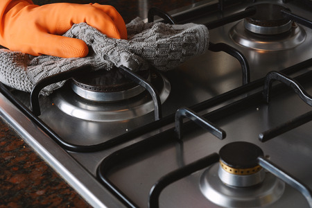 Close up view of hands in rubber gloves cleaning hob. Housework concept.の写真素材