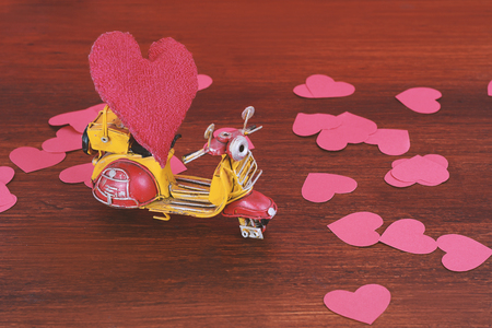 Vintage motorbike carry a red cushion heart on wooden background. Valentine's day. Delivery conceptの写真素材