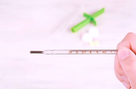 Pills and female hands showing a thermometer. Focus on thermometer. Medicine conceptの写真素材