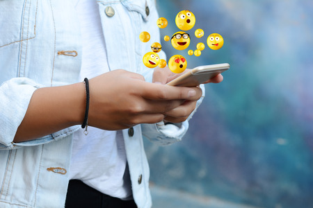 Close-up of woman using smartphone sending emojis. Social concept.の写真素材