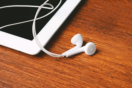 Close up of tablet with earphones on wooden table. Technology conceptの写真素材