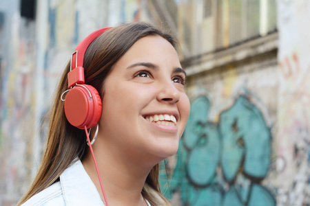 Portrait of young latin woman with red headphones against a graffiti wall.の写真素材