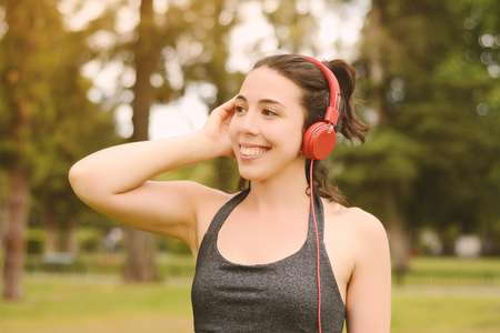 Portrait of young beautiful woman with red headphones listening music. Outdoors. Urban concept.の写真素材