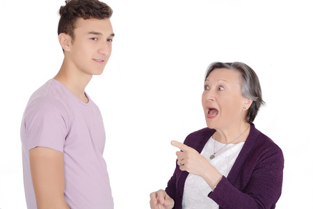 Grandmother arguing with her teenage grandson for bad behavior. Isolated white backgroundの写真素材