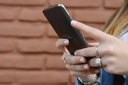 Close up of young women sending message with smartphone on the street.の写真素材