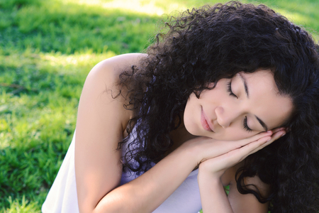 Young latin woman sleeping on the park. Rest and relaxation concept. Outdoorsの写真素材