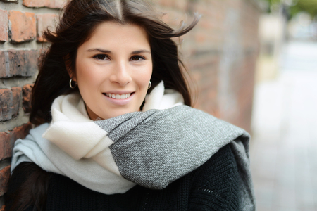 Young beautiful woman winter portrait against a brick wall. Lady wearing stylish winter clothes.の写真素材