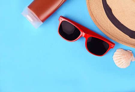 Top view of sunglasses, shells, starfish, sunblock and hat with copyspace. Summer concept. Light blue backgroundの写真素材