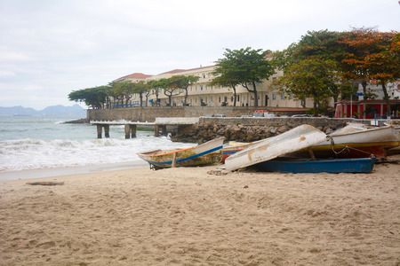 Old boats piled on the shore, on a cloudy day.