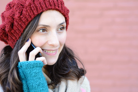 Portrait of young latin woman talking on her mobile phone. Outdoors.の写真素材