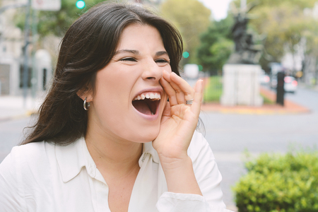 Handsome young woman screaming. Facial expression concept. Outdoors isolated grey background. Positive human emotion facial expression reactionの写真素材