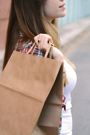 Female hands holding shopping bag outdoors. Woman in shopping. Consumerism and lifestyle concept.の写真素材