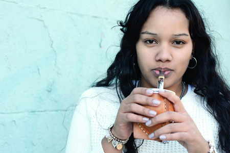 Portrait of Young latin woman drinking traditional Argentinian yerba mate tea. South american...