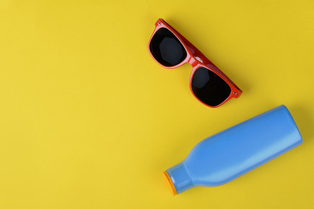 Top view of sunglasses, shells, starfish and sunblock with copyspace. Summer concept. Light blue...