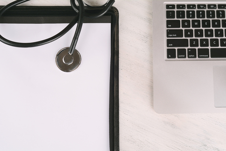 Top view of laptop, notepad and tethoscope at doctor's desk. Modern medicine workplaceの写真素材